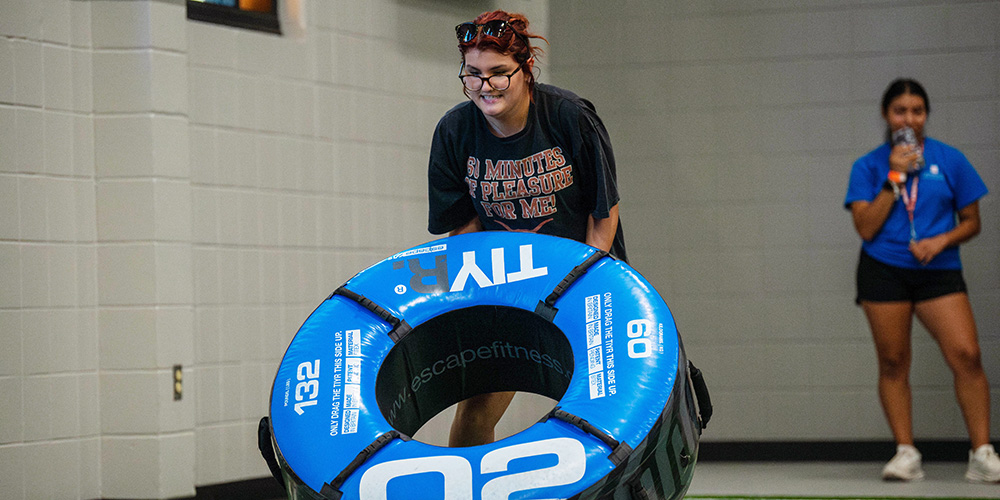 girl flipping tire under supervision